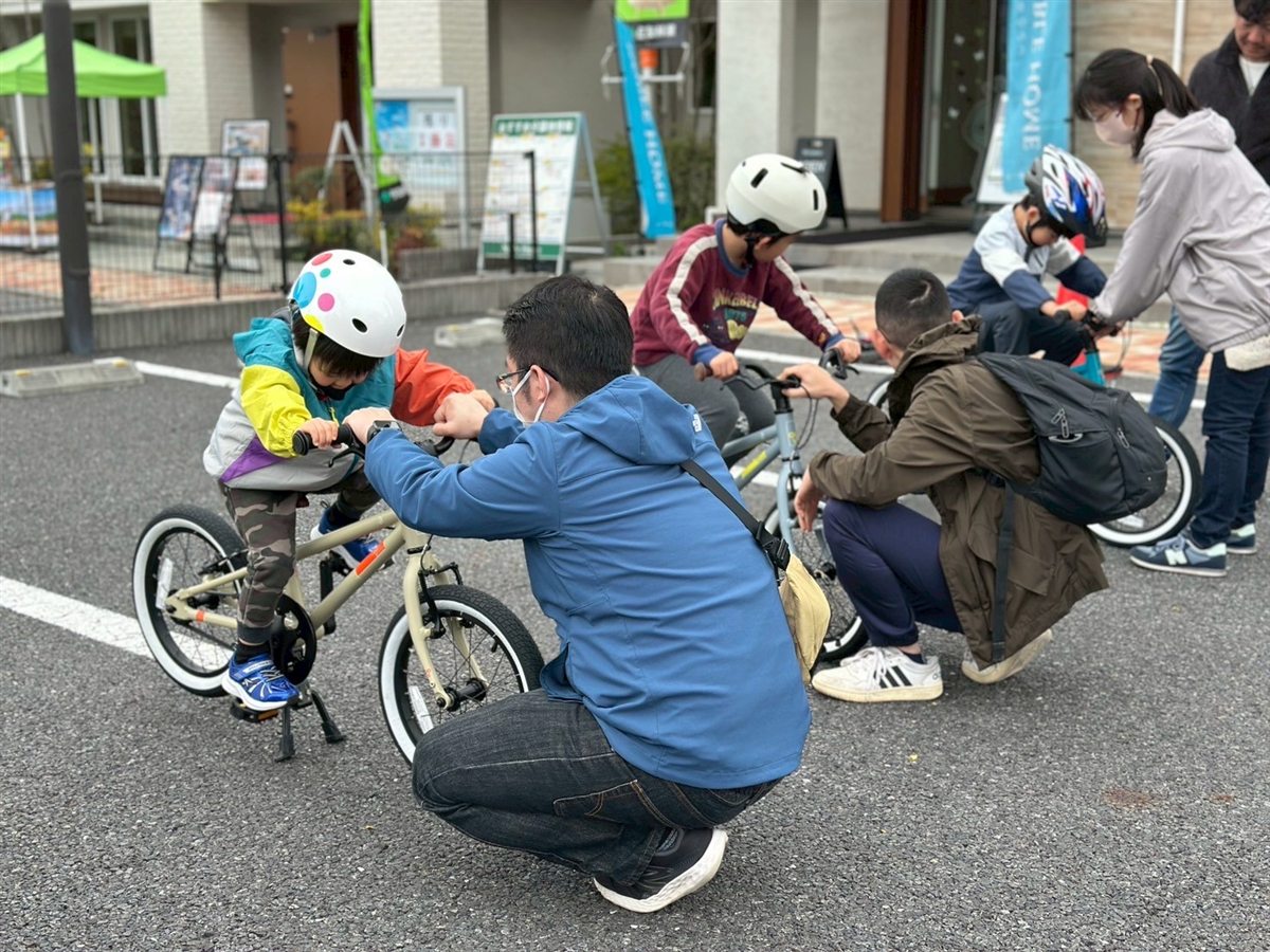 インストラクターが自転車にまたがるお子さまに乗り方を教えている様子
